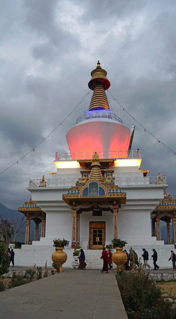 Evening view of a Bhutanese Buddhist stupa with traditional architecture and prayer visitors
