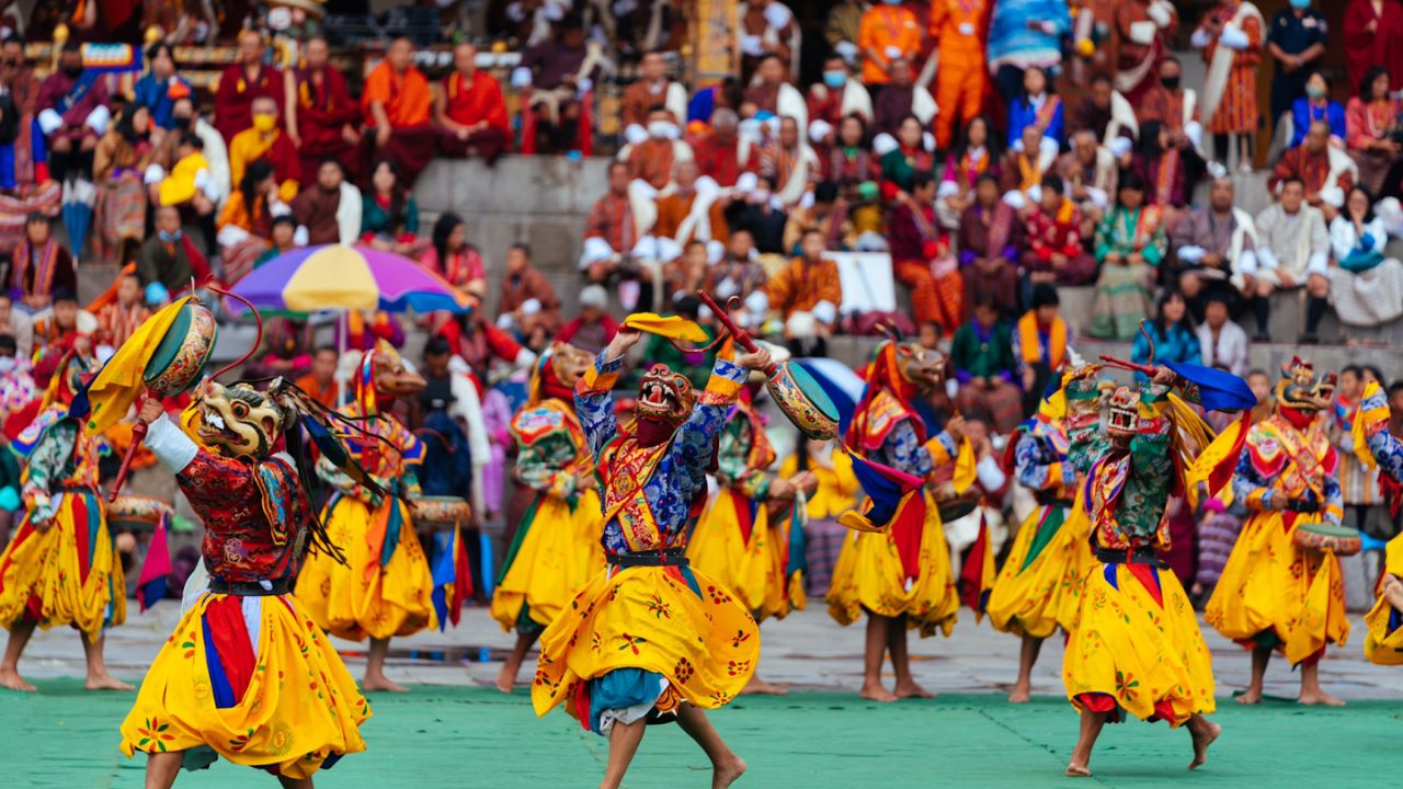 Performers in colorful traditional costumes and masks dance