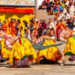 Performers in yellow costumes bow during a dance at the Thimphu Tshechu festival.