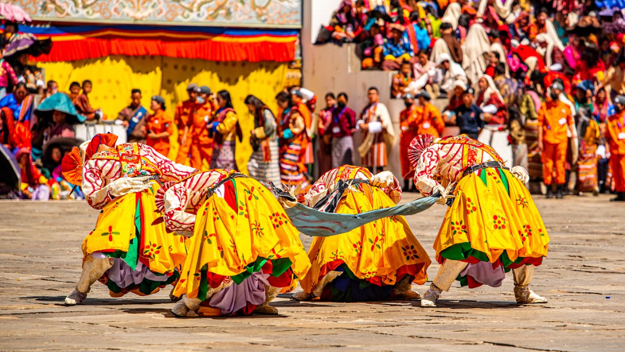 Performers in yellow costumes bow during a dance at the Thimphu Tshechu festival.